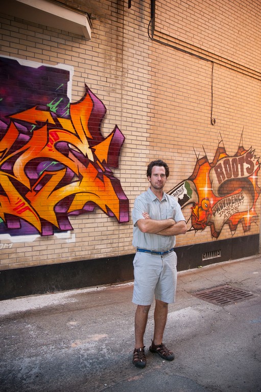 Avenue Concept founder Yarrow Thorne stands in front of a recently commissioned wall at the Roots Cafe downtown