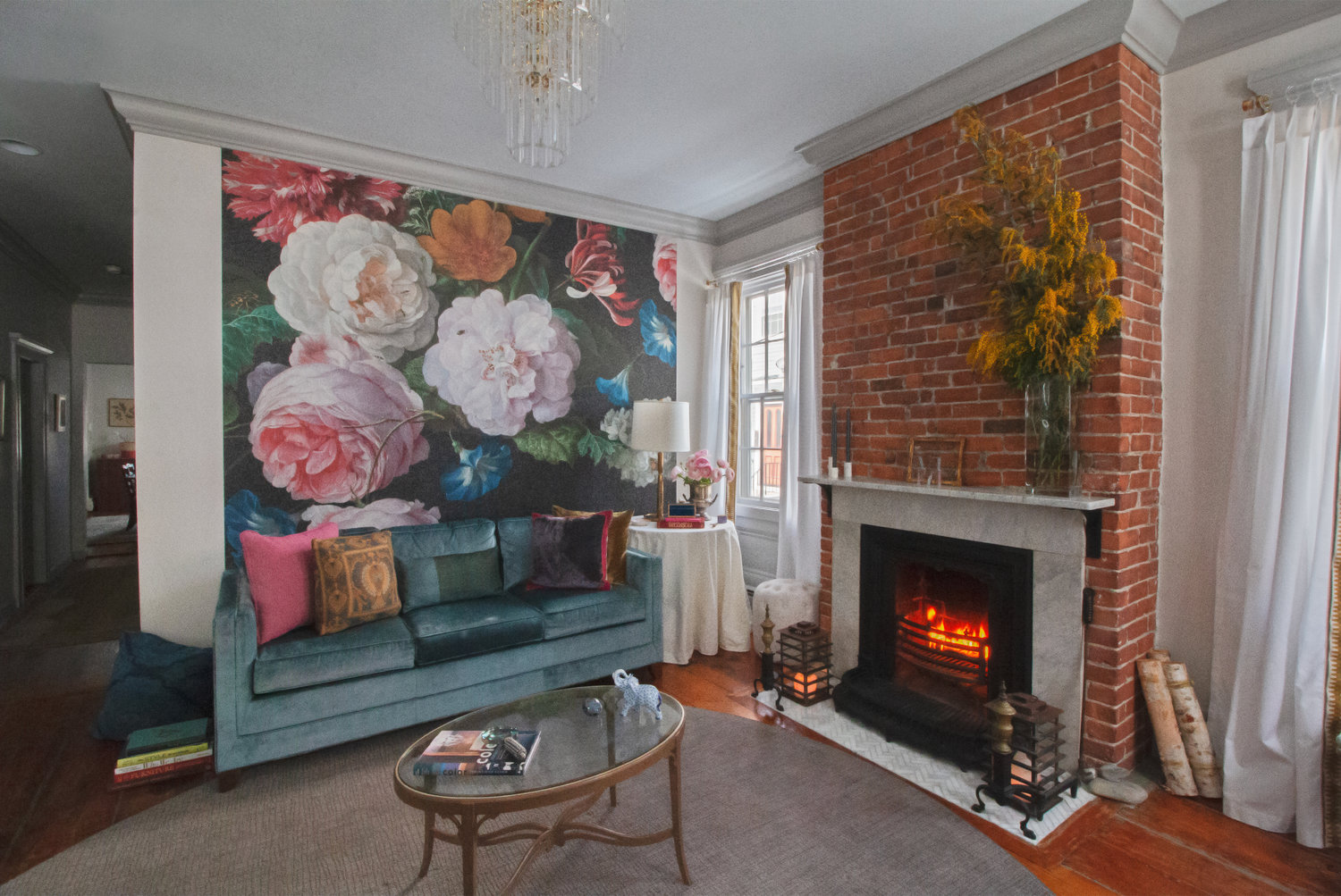 A pair of lanterns from their former home flank a fireplace salvaged from a Beacon Hill demo. The mural creates a stunning backdrop to furnishings like a Mitchell Gold + Bob Williams sofa.